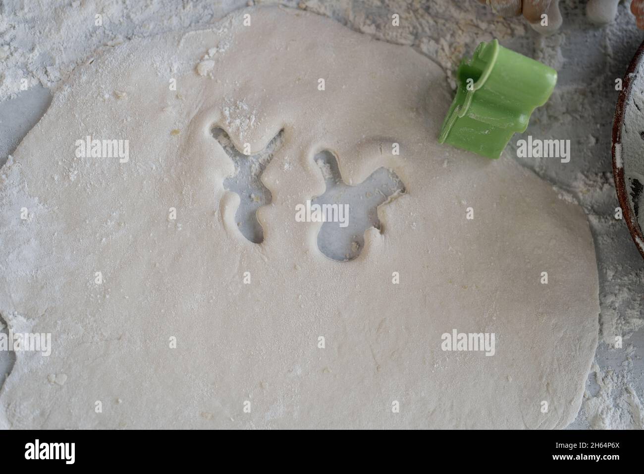 cutting out christmas cookies or gingerbread shape on the table. Sugar cookie mold and raw dough. Stock Photo