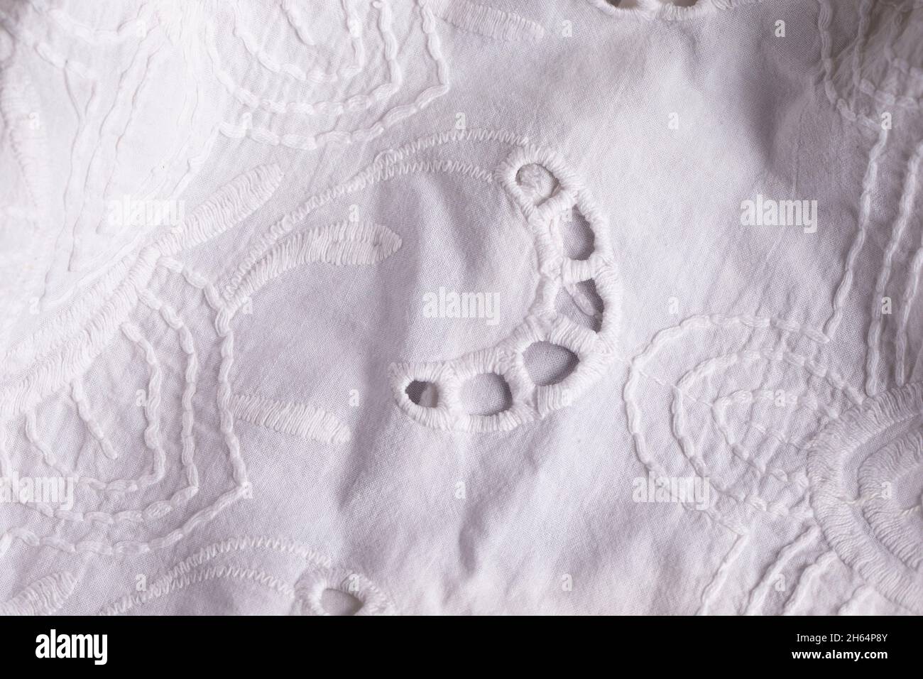 White cotton fabric background with embroidery. A piece of lace fabric