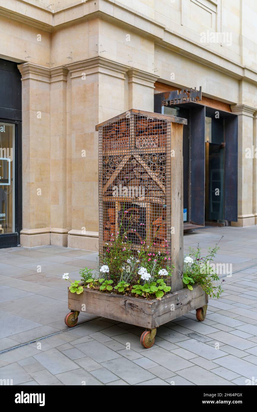 Wooden bug house on a wheeled cart with plants to make a unique urban landscape feature in Bath city centre, Somerset. Stock Photo