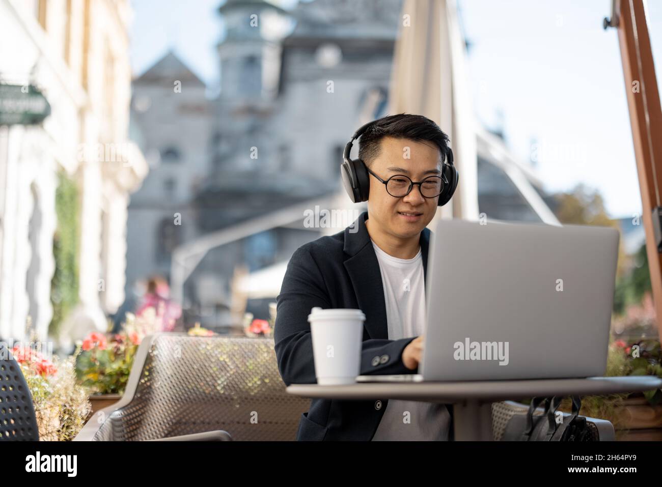 Businessman in earphones working on laptop in cafe Stock Photo