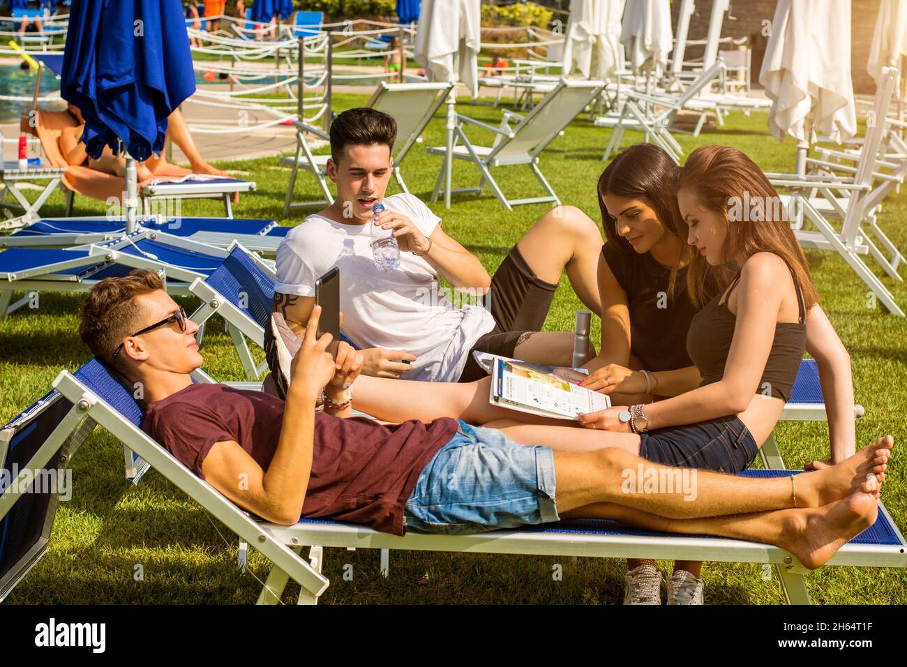 Friends relaxing on sun loungers in beautiful sunny day. Stock Photo