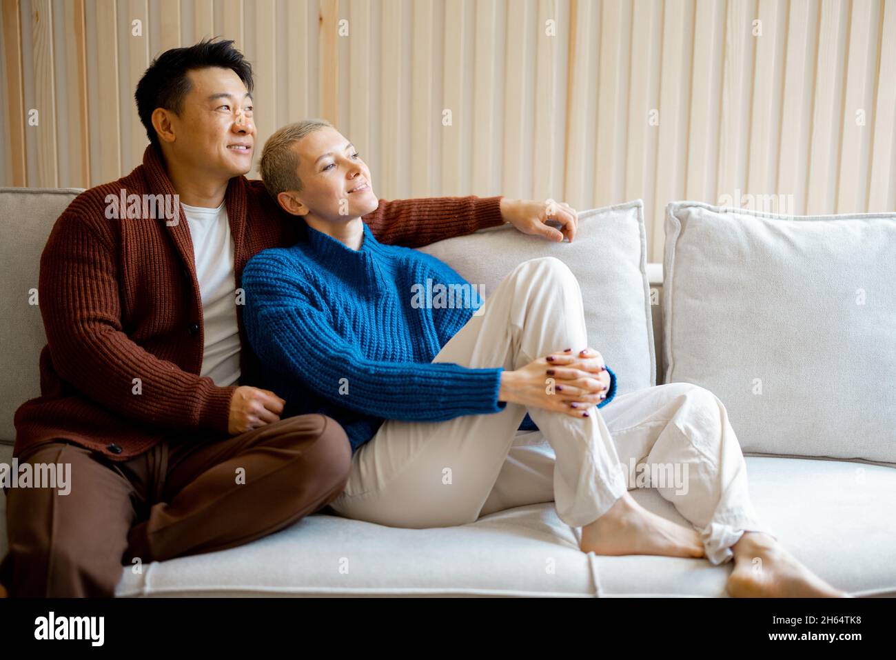 Multiracial couple sit and rest on sofa at home Stock Photo