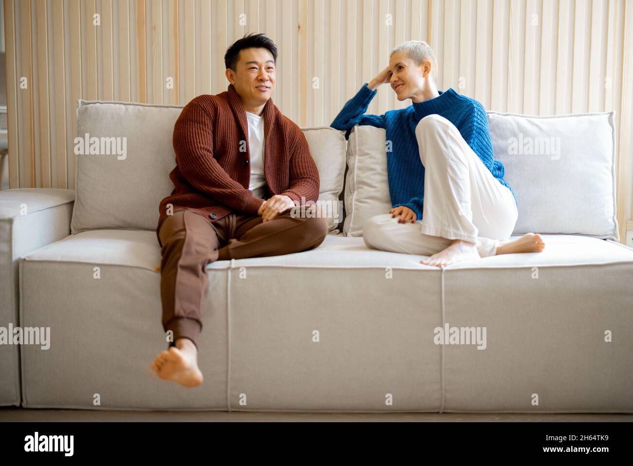 Multiracial couple sit and talk on sofa at home Stock Photo - Alamy