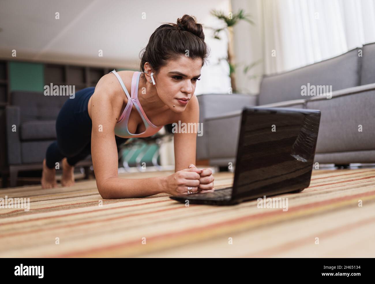 Attractive young Latin woman doing yoga stretching yoga online at home. Self-isolation is beneficial, entertainment and education on the Internet. Hea Stock Photo