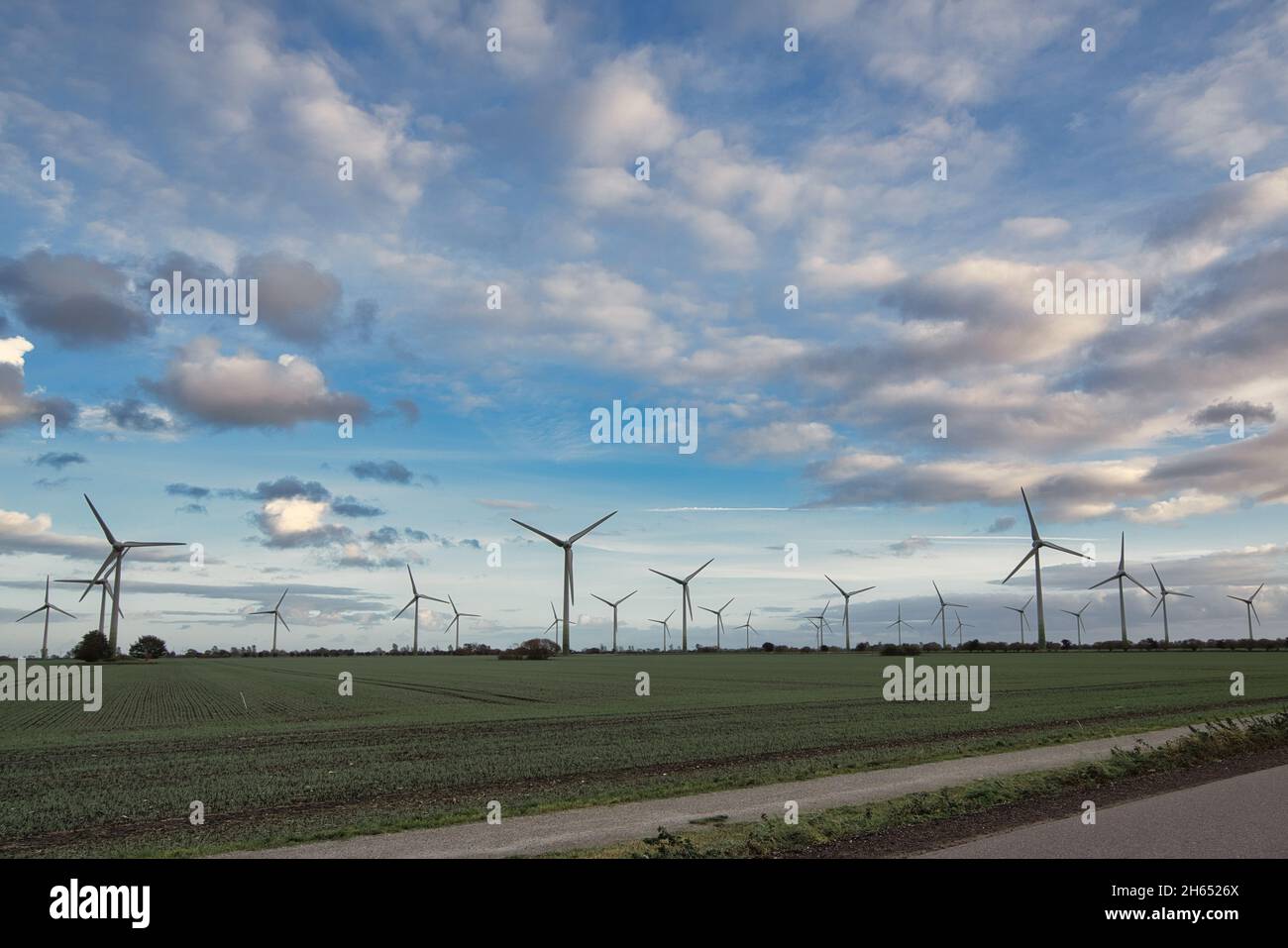 Wind turbines in a green field under a blue sky with clouds Stock Photo ...