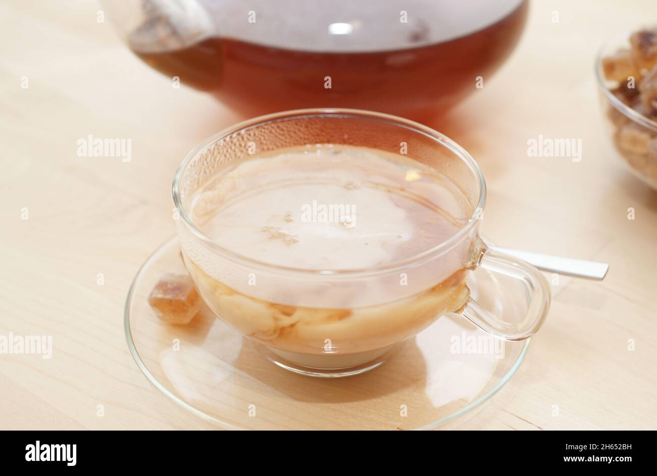 Black tea in a glass with milk in a pot and rock candy sugar Stock Photo -  Alamy