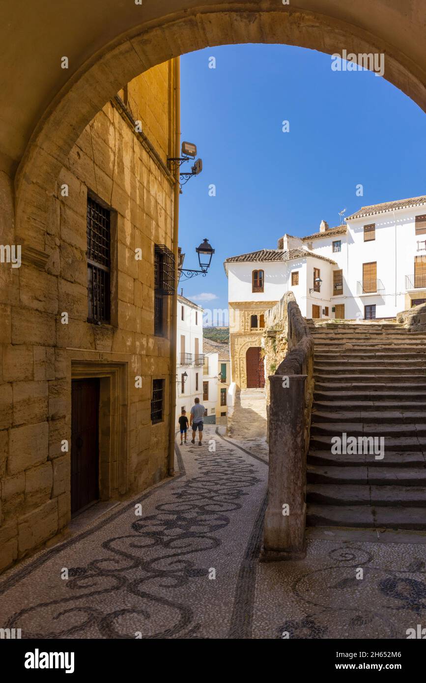 Pedestrians in Calle Baja Iglesia, Alhama de Granada, Granada Province, Andalusia, Spain.  The steps on the right lead up to the Iglesia de la Encarna Stock Photo