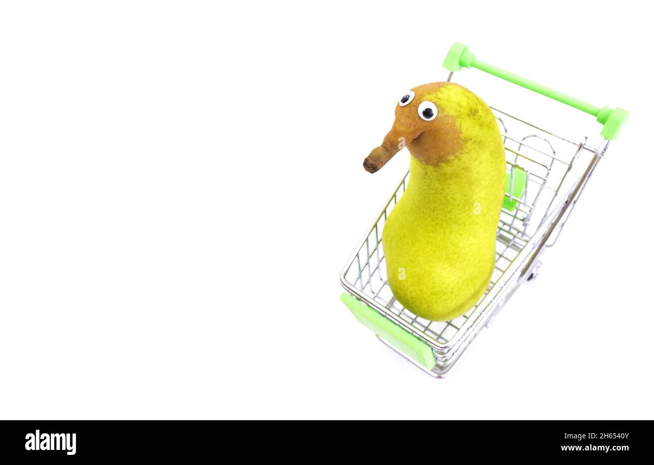 Pear with googly eyes in a toy shopping cart isolated on white background, top view Stock Photo