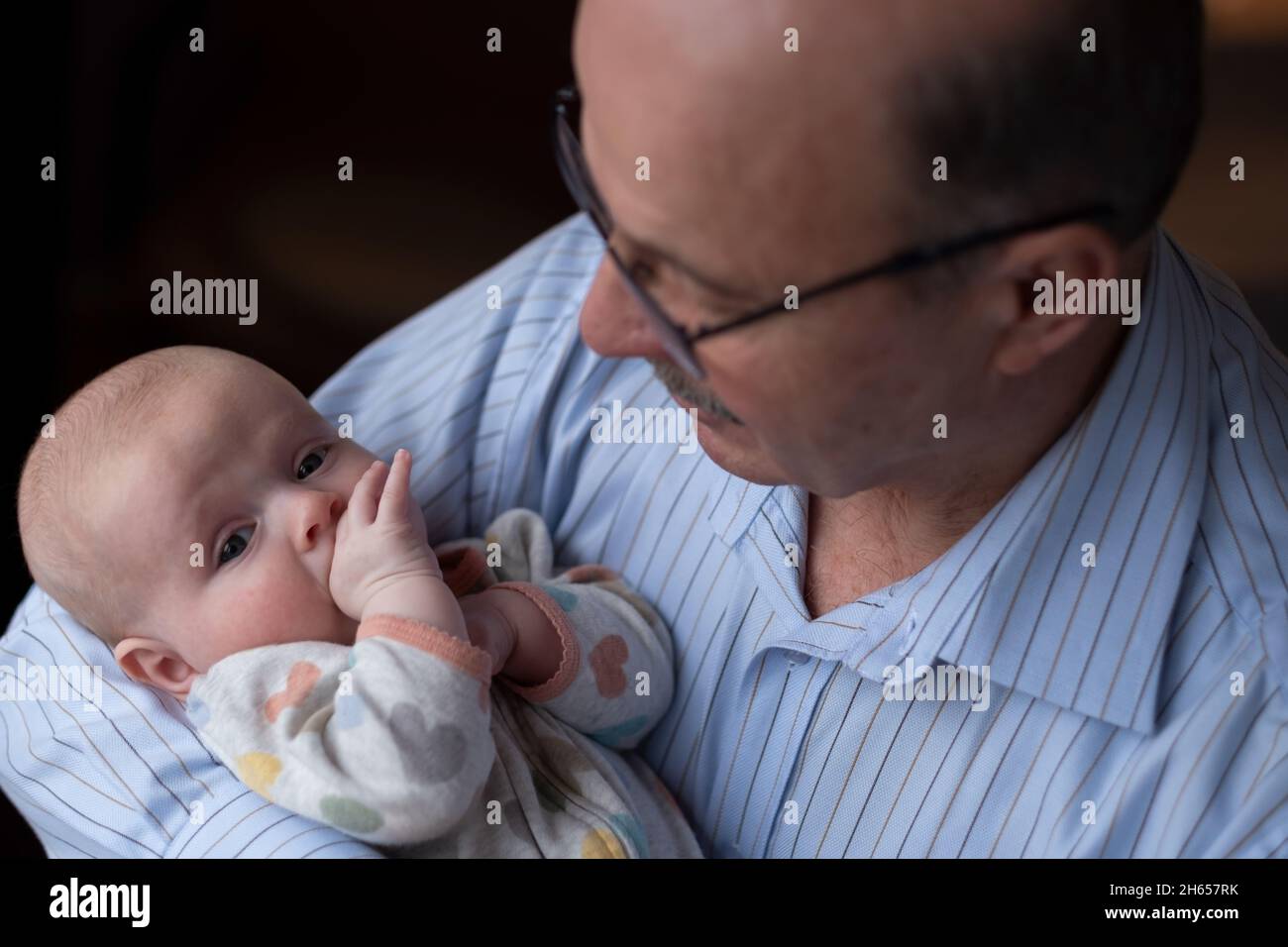 Grandfather holding a beautiful newborn baby girl Stock Photo
