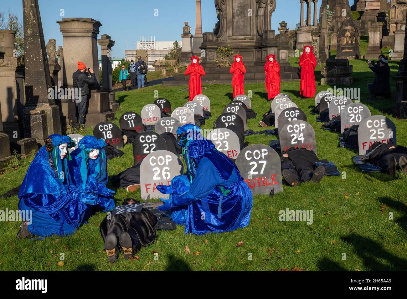 The Red Rebel Brigade join the Blue Rebel Brigade at the Glasgow Necropolis graveyard for the funerary of COP26. The weeping climate activists feel that COP26 is a failure and have held a mock funeral for the summit. COP26 is laid to rest in a grave alongside all of the previous COP summits.COP27 is labelled as futile. Stock Photo