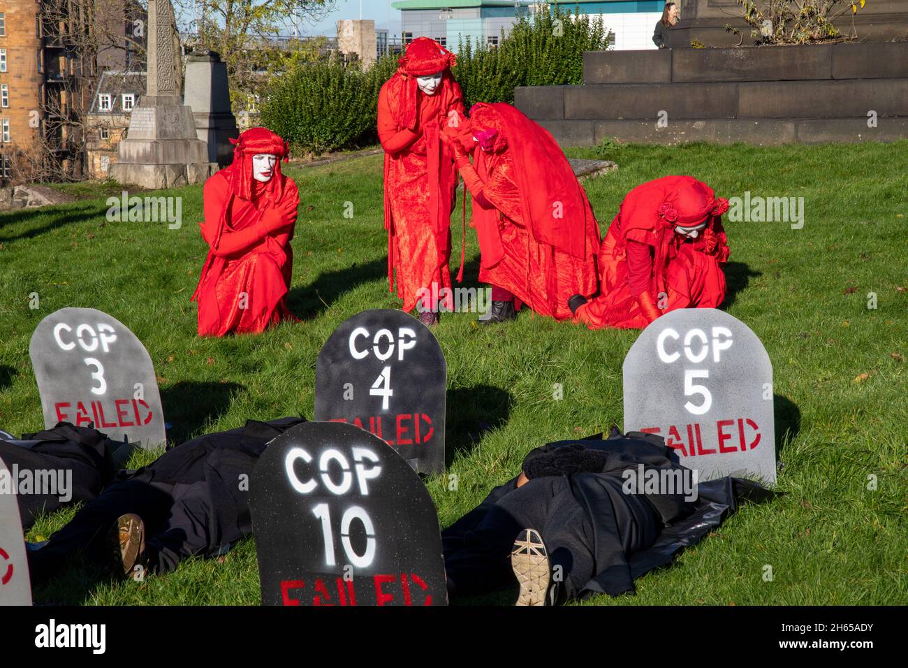 The Red Rebel Brigade join the Blue Rebel Brigade at the Glasgow Necropolis graveyard for the funerary of COP26. The weeping climate activists feel that COP26 is a failure and have held a mock funeral for the summit. COP26 is laid to rest in a grave alongside all of the previous COP summits. Stock Photo