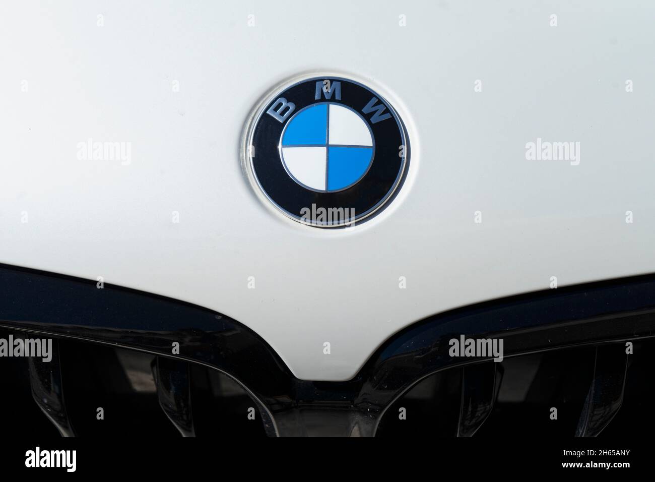 Close-up on the BMW logo on the front of the white car parked on the street. Automotive Industry Stock Photo