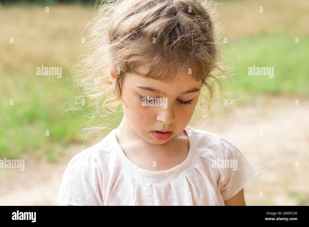 Beautiful  Little girl play with sand in park on a summer day at sunset. Stock Photo