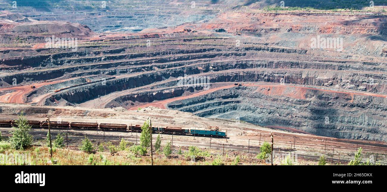 Iron ore extraction in the quarry of the Mikhailovsky mining and processing plant, a train travels inside the quarry Stock Photo