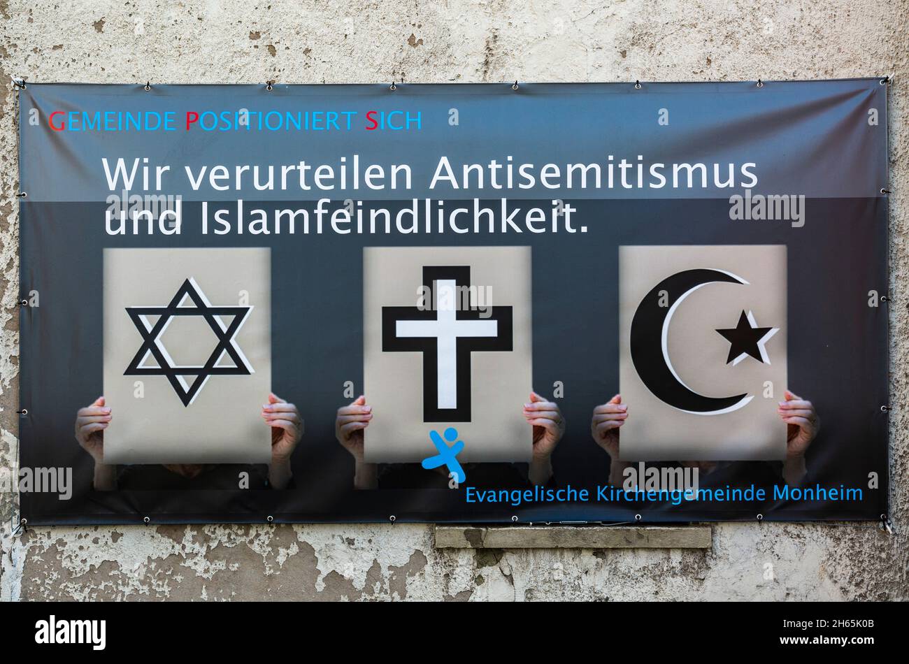 Germany, Society, Religion, Christian Morality, on a banner the Evangelical Congreation of Monheim am Rhein disapproves strongly antisemitism and hostility to Islam, symbols for Judaism and Christianity and Islam are compared as coexistent and equally Stock Photo