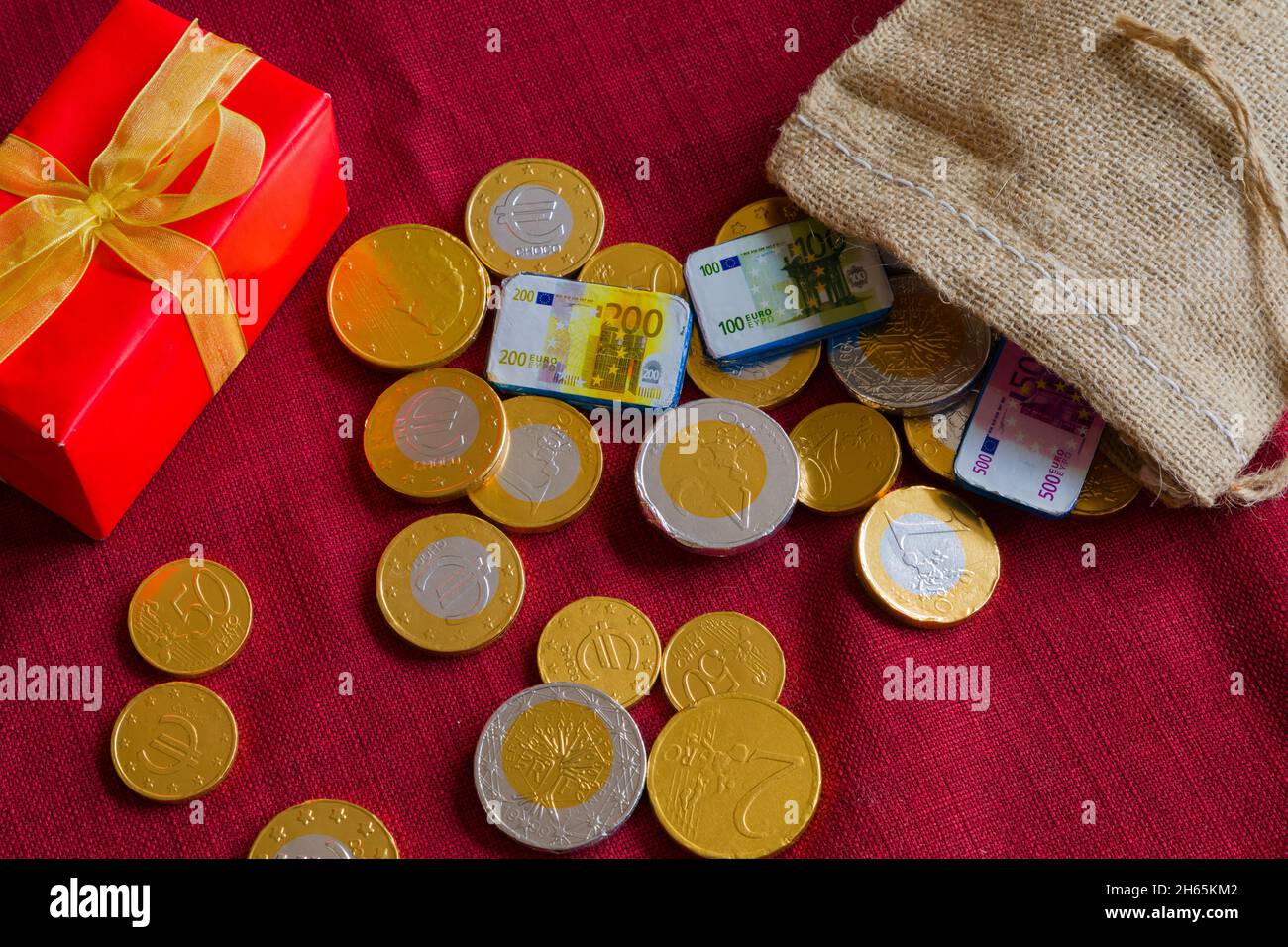 Chocolate coins scattered around, a sack and a present. Concept for expensive holidays like Christmas and Sinterklaas Stock Photo