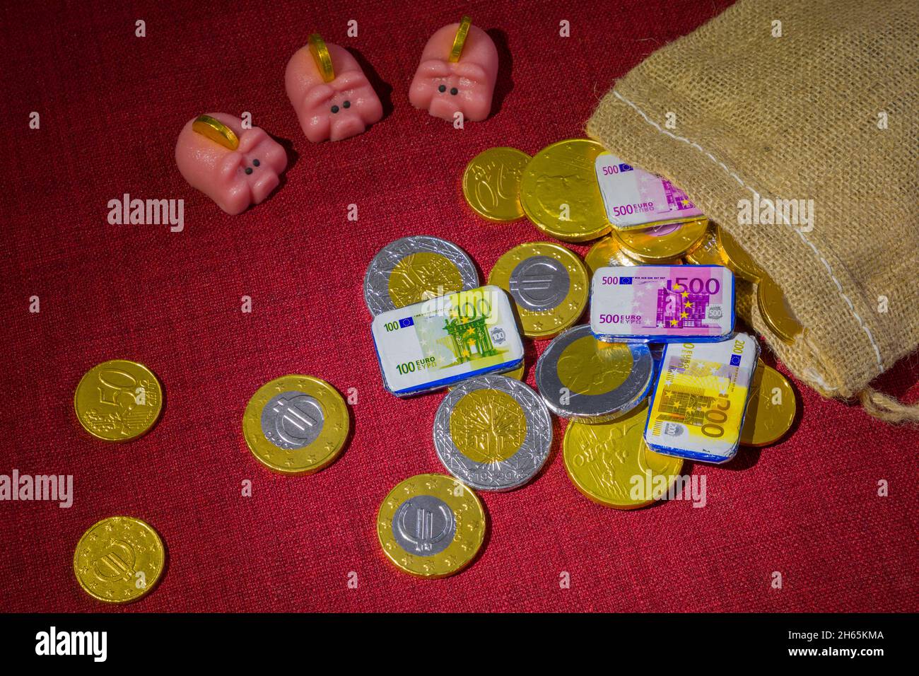 Chocolate coins scattered around, a sack and marzipan piggy banks. Concept for expensive holidays like Christmas and Sinterklaas Stock Photo