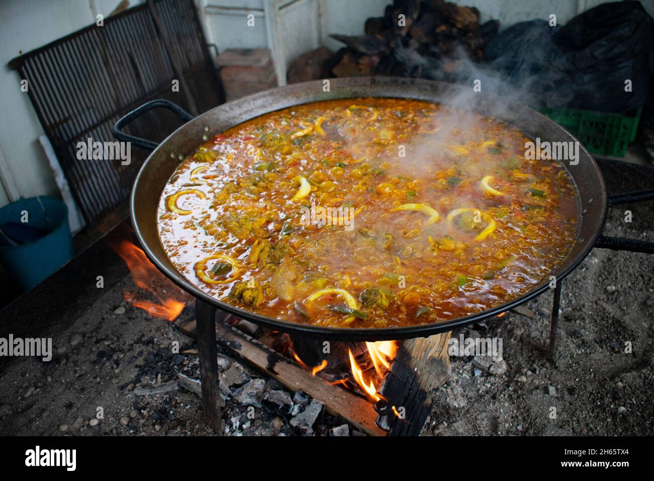 Tasty Spanish paella cooking over a wood fire at a Nerja beach restaurant Typical Spanish cuisine cooked in the old fashioned way  Landscape aspect sh Stock Photo