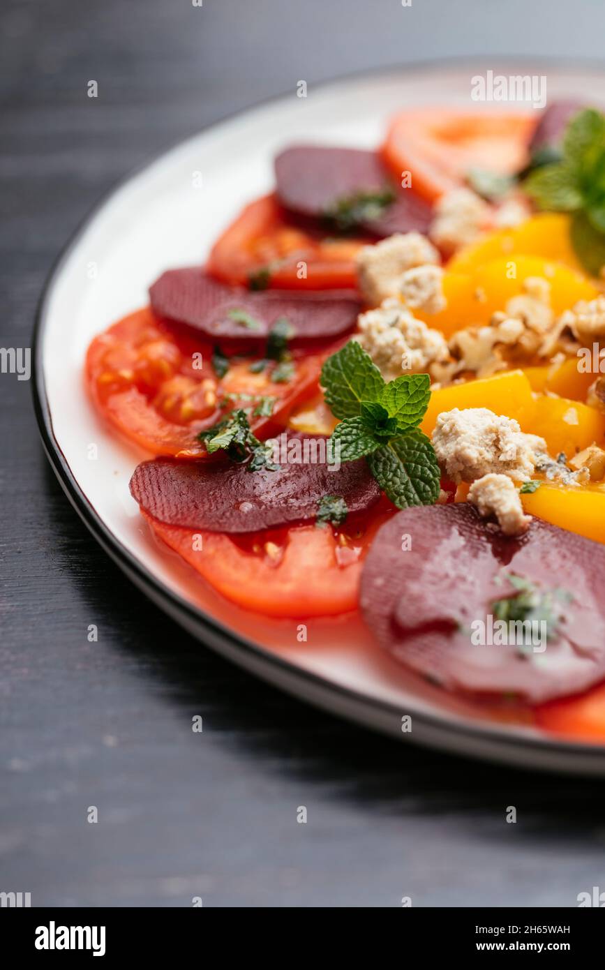Plate with a home made vegan beet, tomato, and peach salad. Stock Photo