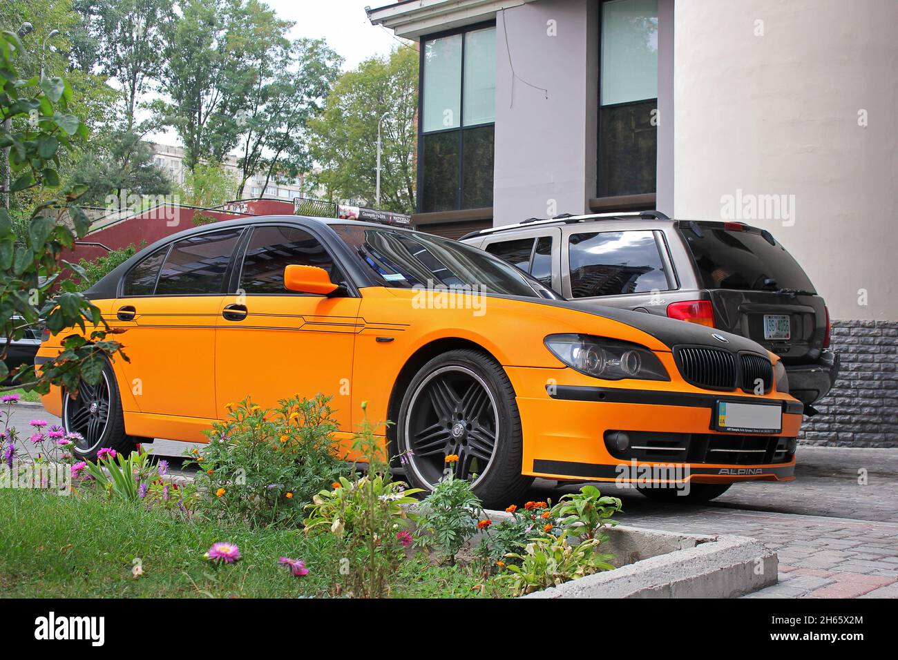 Kiev, Ukraine - September 2, 2017: BMW 7 Series Alpina in an orange matte film against the background of other cars and a house Stock Photo