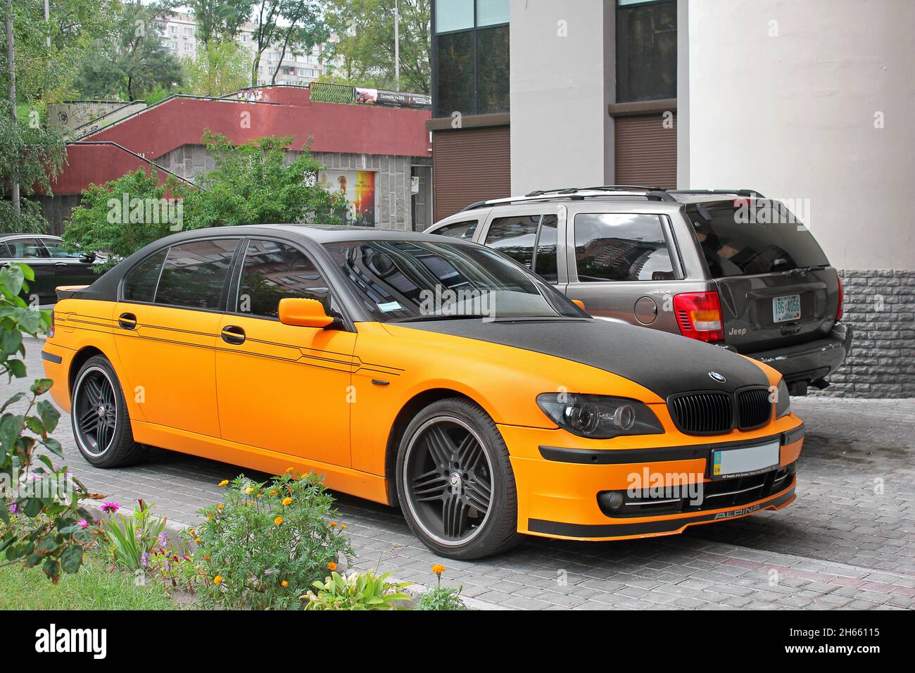 Kiev, Ukraine - September 2, 2017: BMW 7 Series Alpina in an orange matte film against the background of other cars and a house Stock Photo