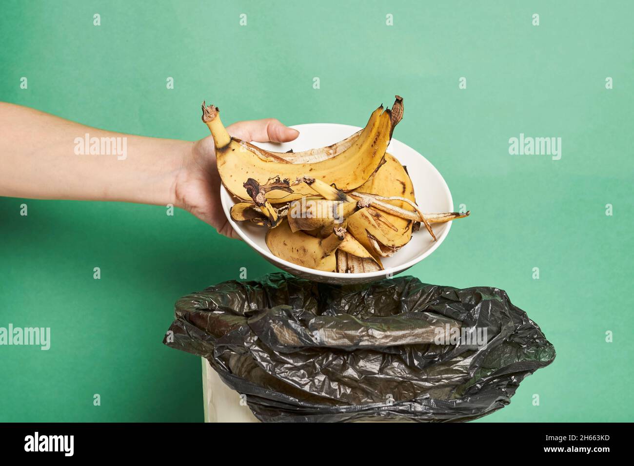Woman throwing banana peels in trash can. Throw out banana peels in garbage. Banana skin in
