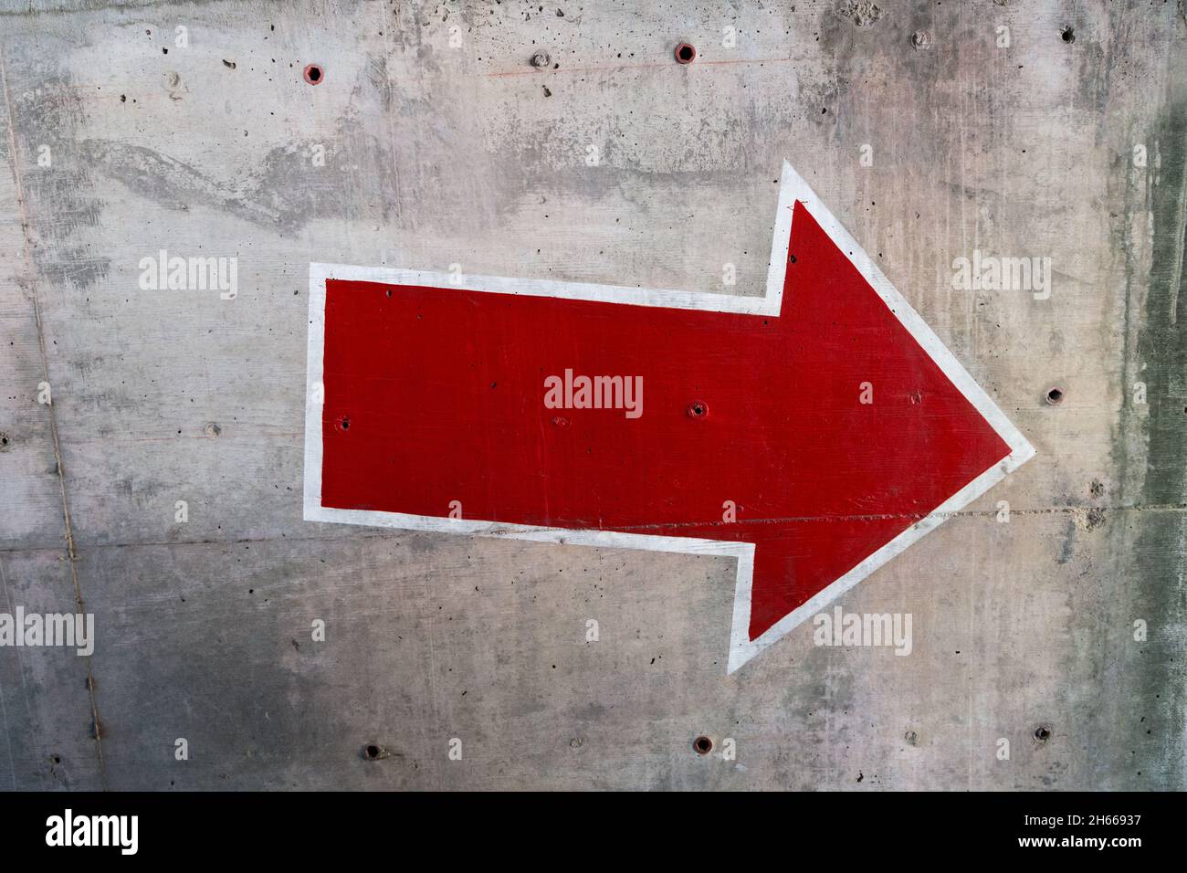 Red arrow painted on concrete wall Stock Photo