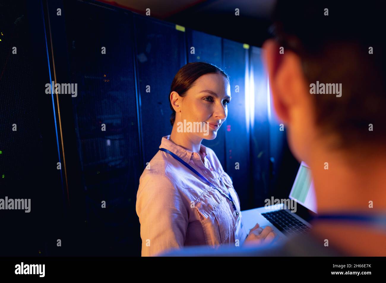 Caucasian female engineer using laptop in computer server room Stock Photo