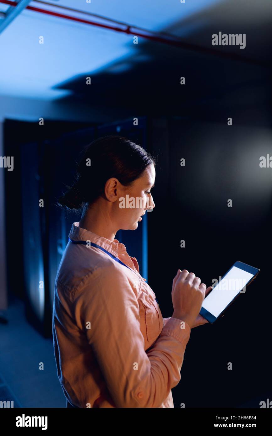 Caucasian female engineer using digital tablet in computer server room Stock Photo