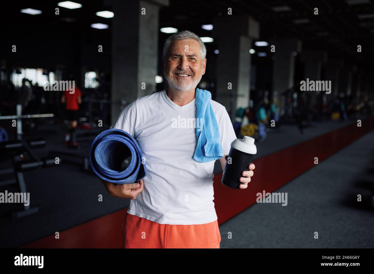 Old man with bottle of water, towel and mat in gym Stock Photo - Alamy