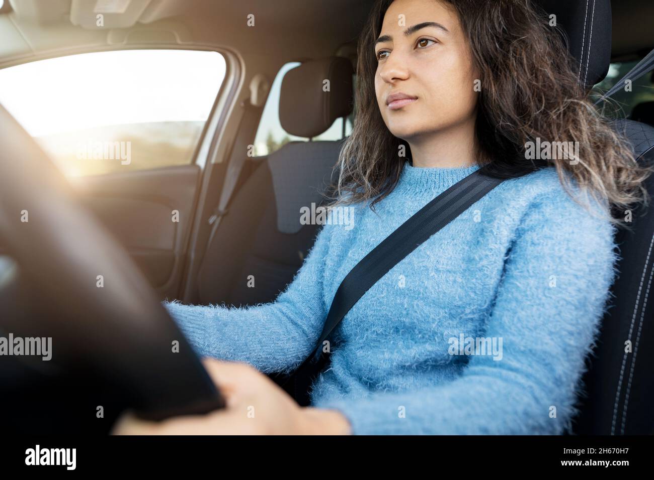 Young woman driving car on the road. Driver licence and driving safety concept. Stock Photo