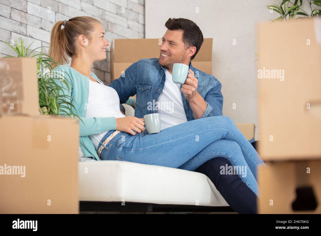 happy couple taking break unpacking on moving day Stock Photo