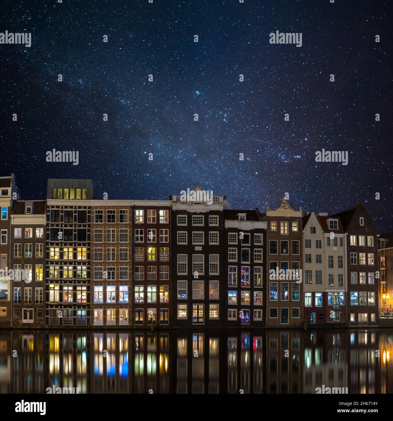 Night landscape with famous houses in Amsterdam, stars in sky and reflection in water, cityscape Stock Photo