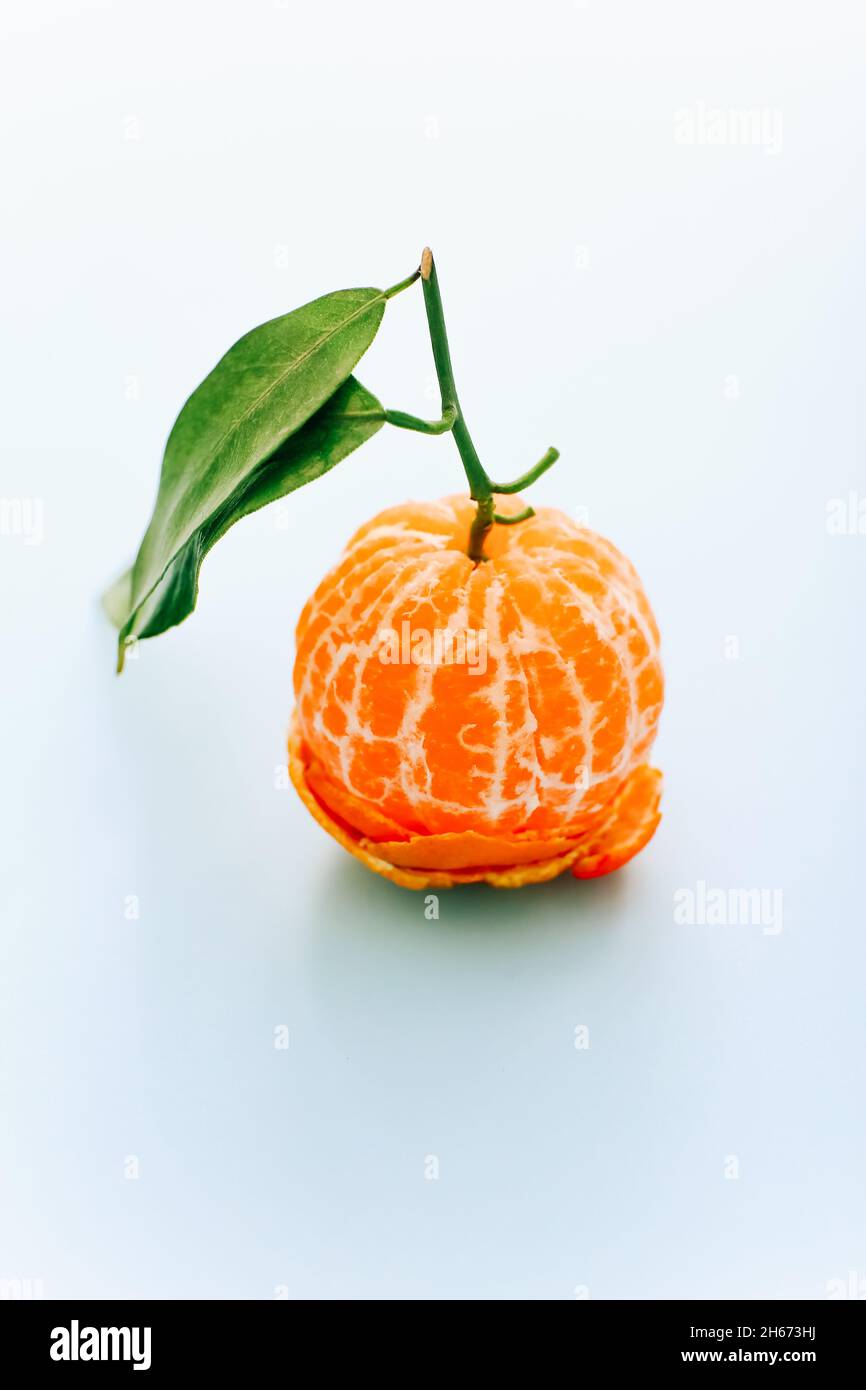 Peeled tangerine with leaves on light background Stock Photo