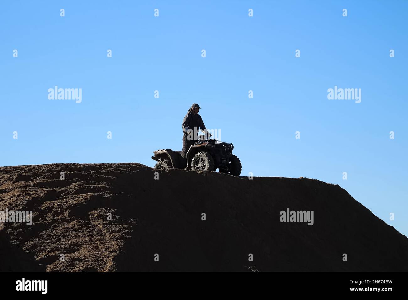 silhouette of a man on a quad against a blue sky Stock Photo
