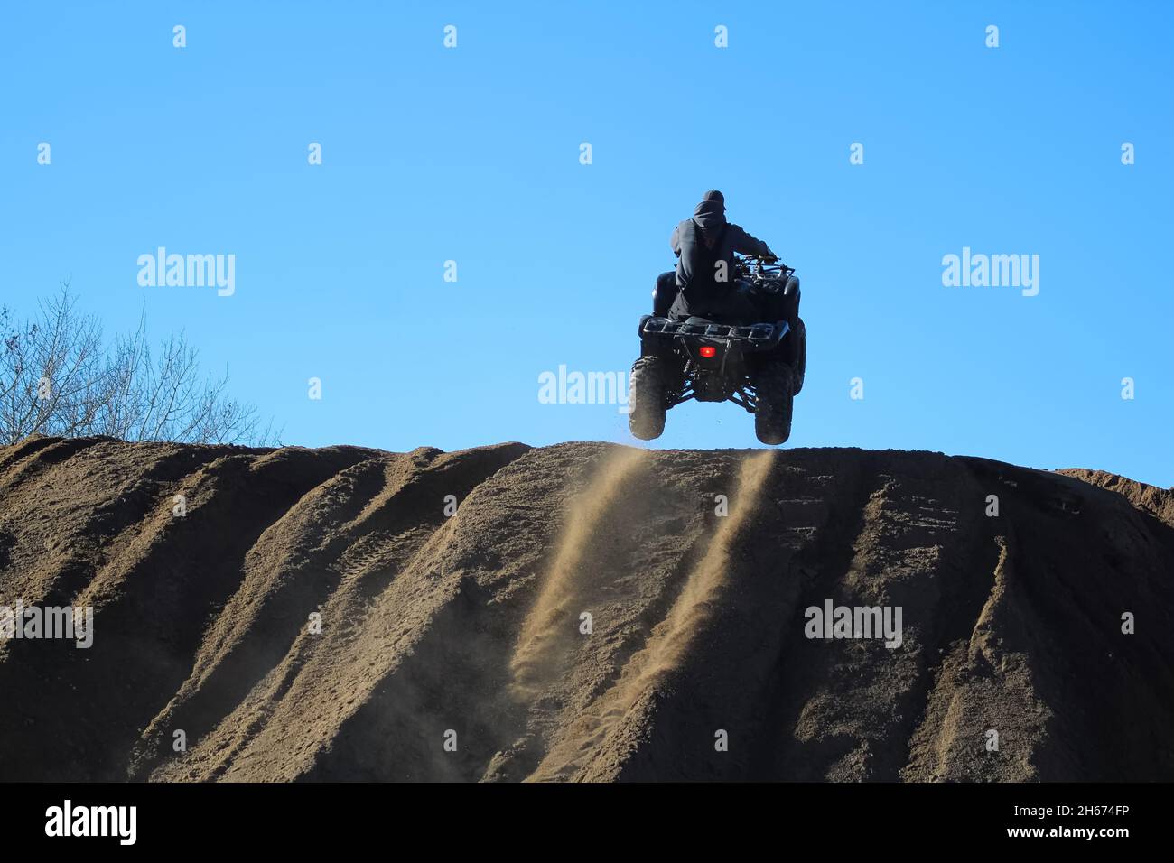 silhouette of a man jumping with a quad against a blue sky Stock Photo