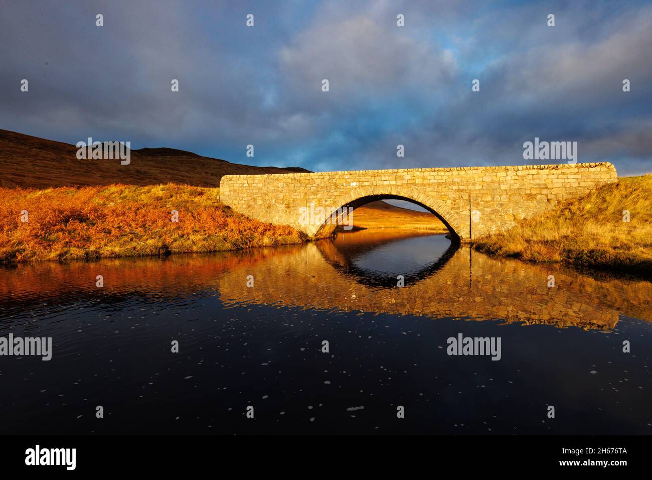 A stone bridge supporting route A836 spans Lon Achadh na h-Albhne, a river connecting Loch Coulside to Loch Loyal in Sutherland County, Scotland. Stock Photo