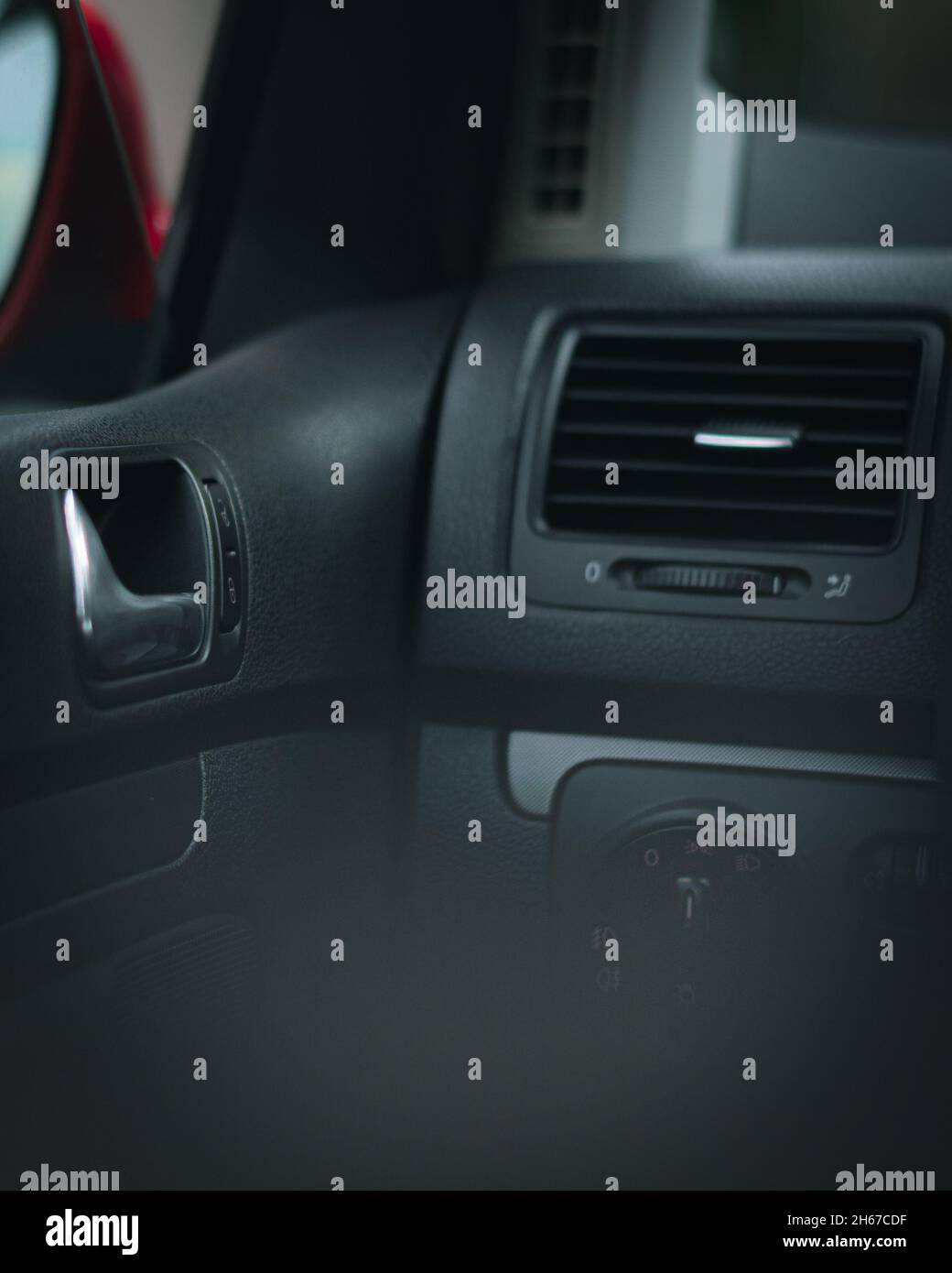 Vertical view of a car dashboard air vent black materials red mirror