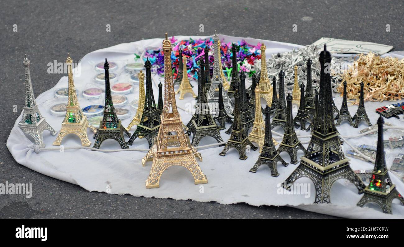Miniature Eiffel Tower replicas and other souvenirs are displayed for sale by a street vendor in Paris. Stock Photo