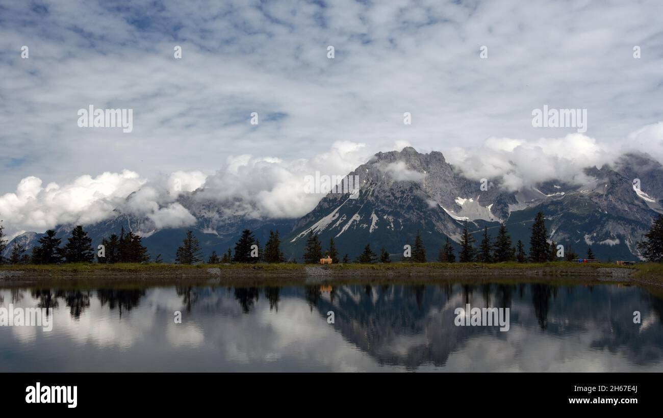 Reflection of “Wilder Kaiser“ mountains in Astberg Lake on a cloudy day. Going, Austria. Stock Photo