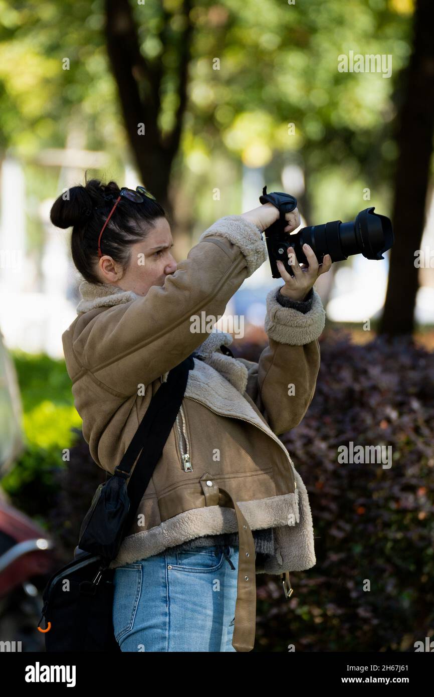 A professional female photographer taking a photo sideways Stock Photo