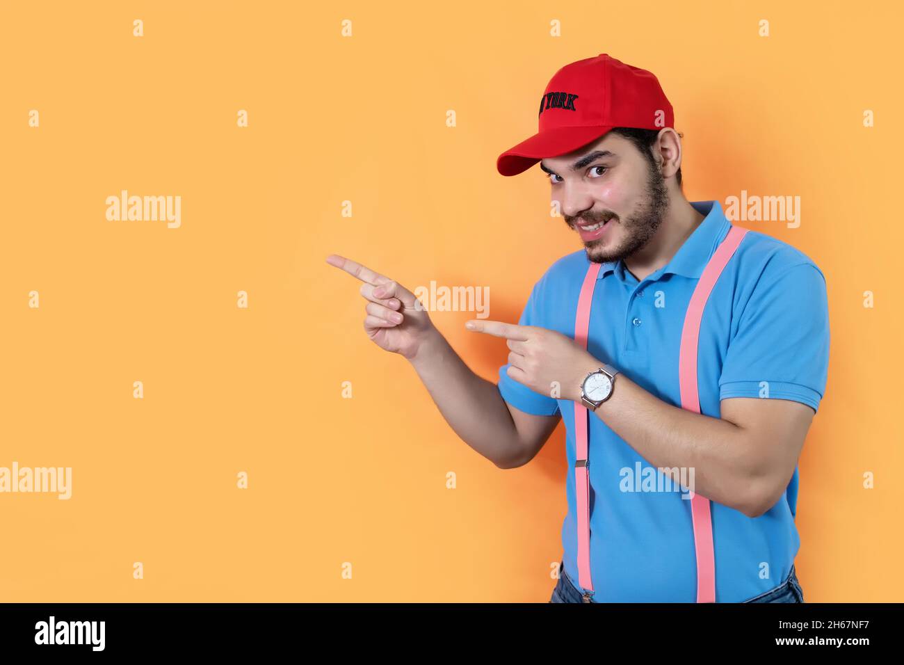 Bearded man pointing something out with his fingers aside on the orange background with a copy space Stock Photo
