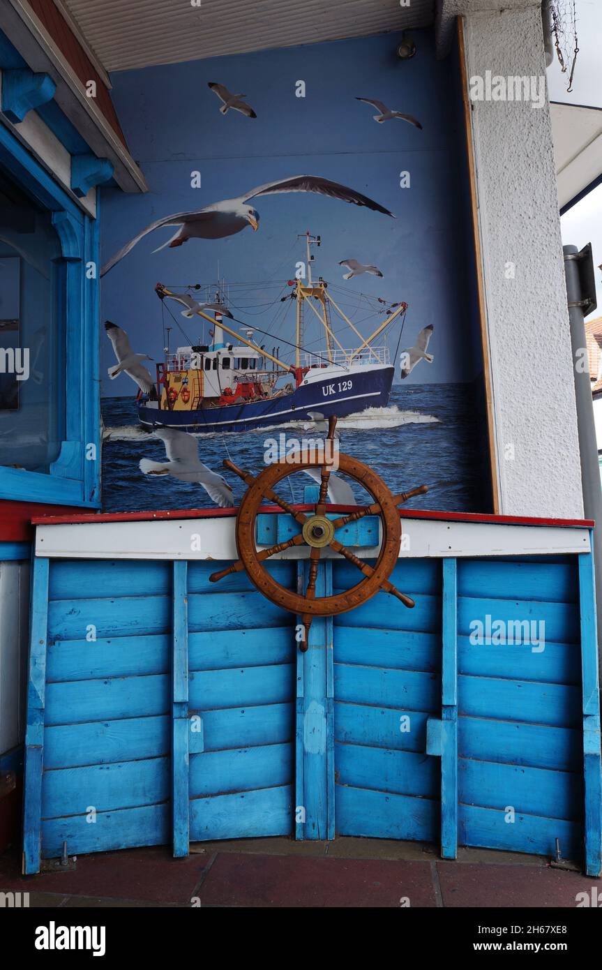 Boat mural on a wall and a ship's helm in Sheringham Norfolk Stock
