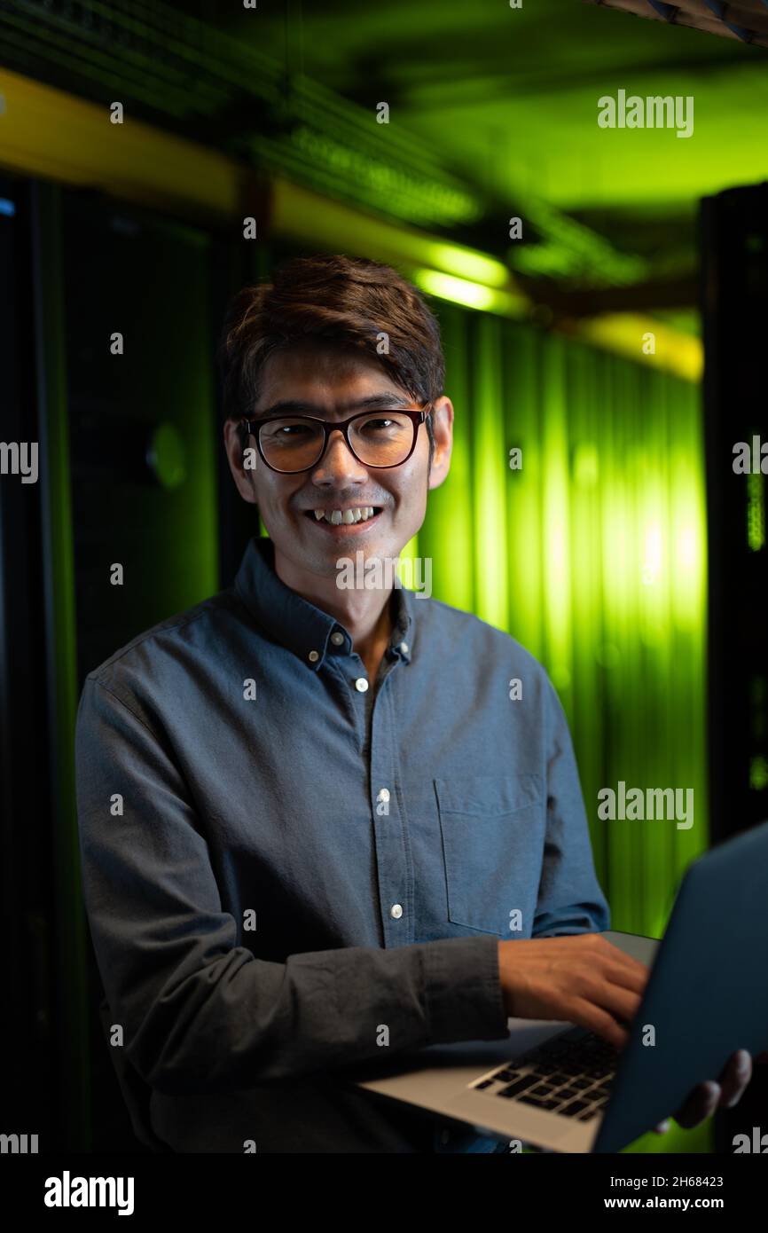 Portrait of asian male engineer smiling while using laptop in computer ...