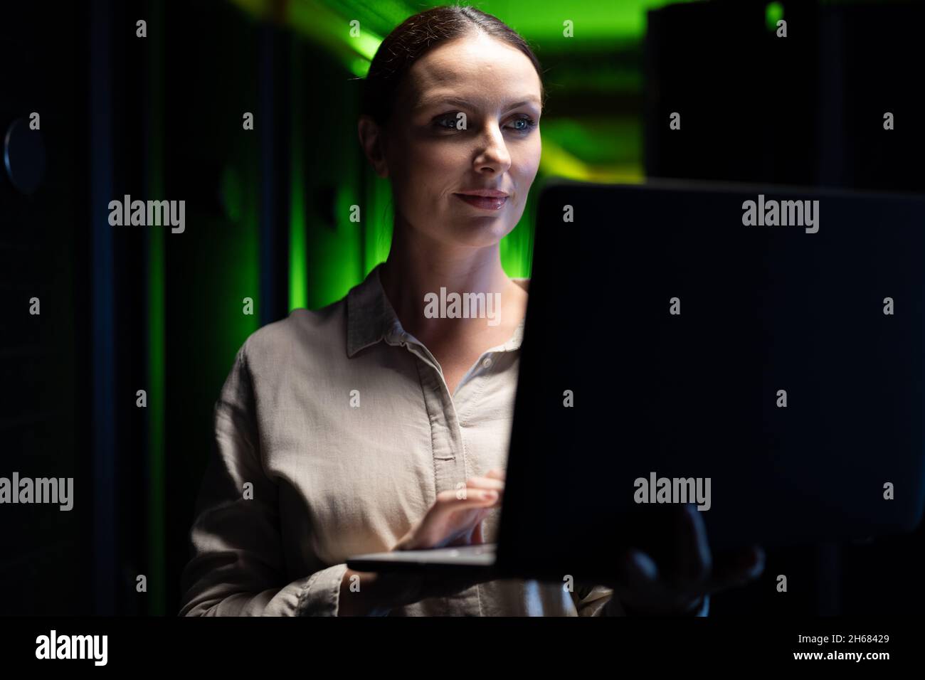 Caucasian female engineer using laptop in computer server room Stock Photo