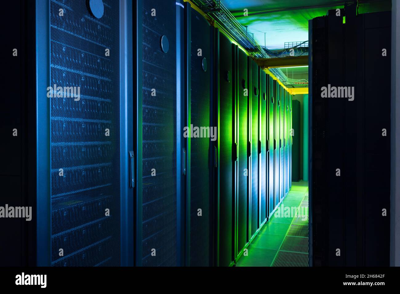 Data center with multiple rows of fully operational server racks Stock Photo