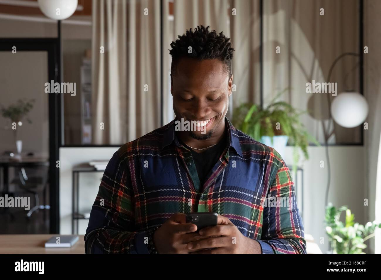 Smiling young african man using cellphone applications. Stock Photo