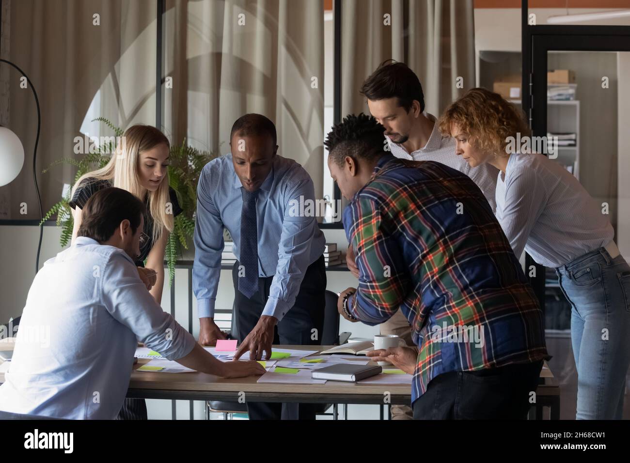 Concentrated young mixed race teammates analyzing paper reports. Stock Photo