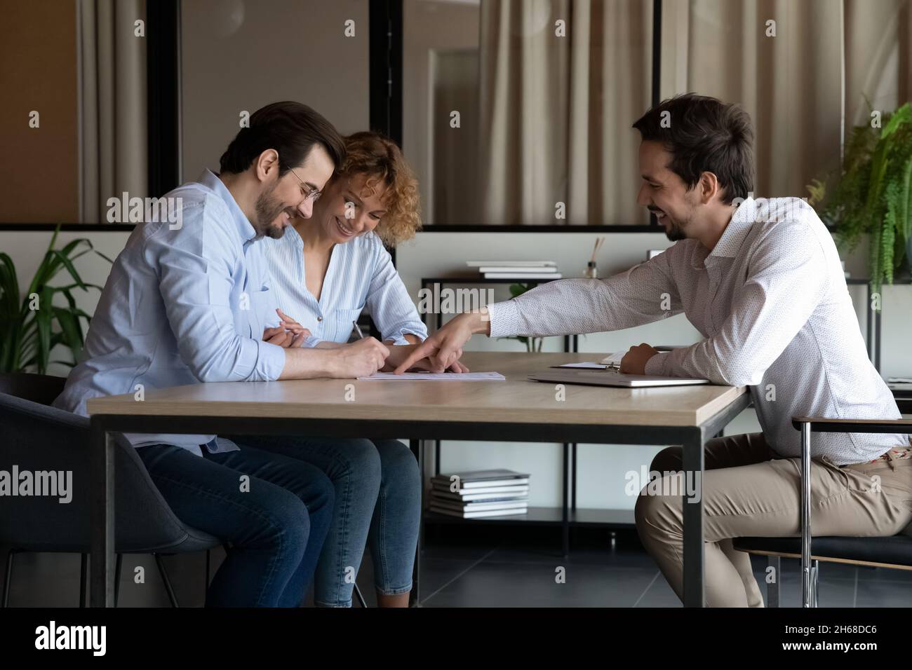 Smiling young specialist making agreement with clients. Stock Photo