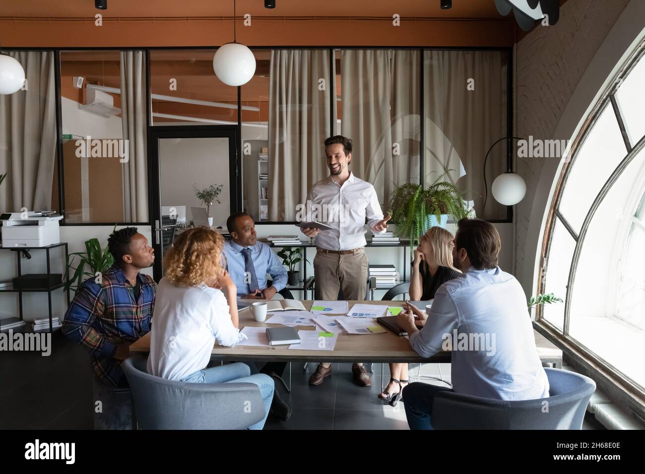 Happy young hispanic male leader holding negotiations meeting. Stock Photo